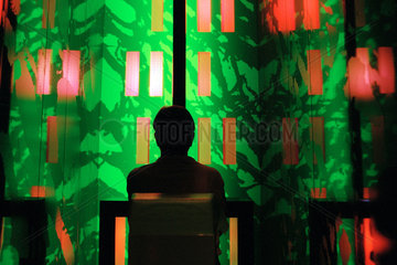 Silhouette eines Mannes vor farbig beleuchteter Wand