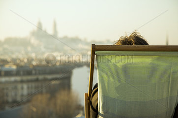 Person sitting in deckchair  looking at view of city