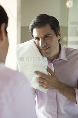 Man looking in mirror  drying his face with a towel