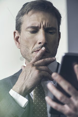 Businessman looking at digital tablet with furrowed brow
