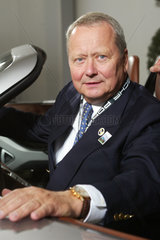 Doktor Wolfgang Porsche im Portrait am Auto