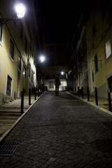 Man walking on cobblestone street at night