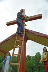 Ein Mann beim Schmuecken eines Kreuzes  Polen