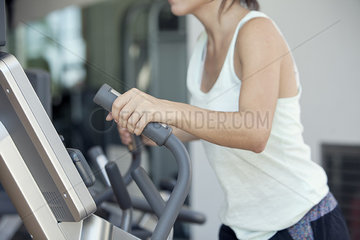 Woman using exercise machine in fitness club  cropped