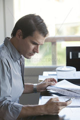 Man looking at smartphone while reading document