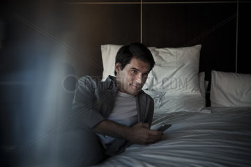 Man relaxing on bed with smartphone