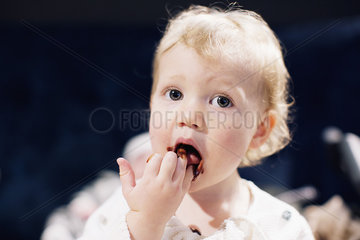 Toddler licking chocolate syrup from fingers