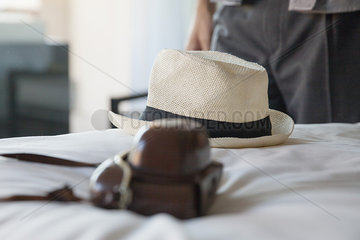 Camera and straw hat on bed in hotel room