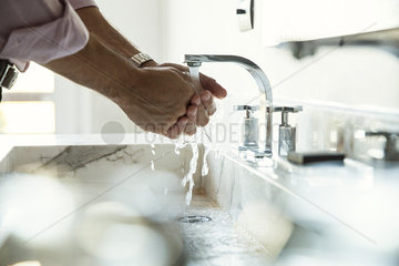 Man washing hands in bathroom sink  cropped