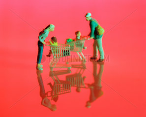 Miniaturfiguren mit Einkaufswagen vor roter Flaeche