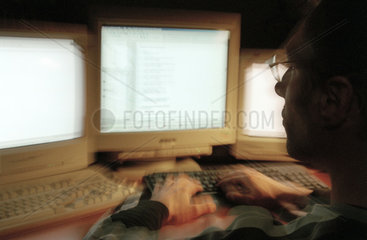 Ein junger Mann sitzt vor Computermonitoren