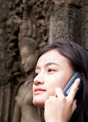 Angkor Wat  Kambodscha  eine junge Asiatin telefoniert mit ihrem Handy in der Anlage Bayon