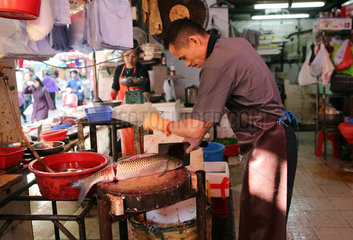 Hong Kong  China  Fischverkaeufer zerteilt einen Fisch auf einem Wochenmarkt