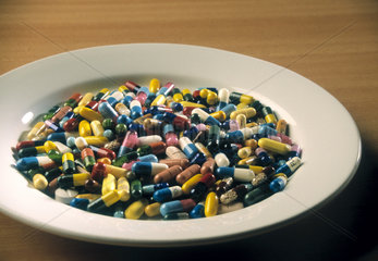Ein Teller voller Tabletten und Kapseln  in verschiedenen Farben und Groessen