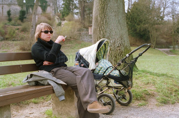 Rauchende Mutter mit Kinderwagen.