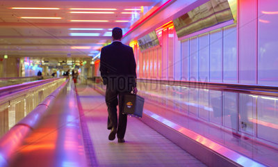 Ein Mann in einem Gang des Muenchener Flughafen auf einer Rolltreppe