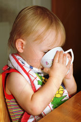 Ein Kleinkind trinkt aus einer Tasse