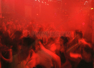 Besucher eines Clubs beim Tanzen in farbigem Licht