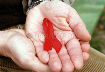 Rote AIDS-Schleife als Solidaritaetssymbol in Maennerhaenden