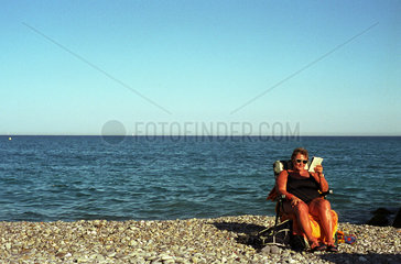 Eine Frau liest ein Buch am Strand von Nizza