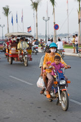 Phnom Penh  Kambodscha  eine Frau mit Mundschutz faehrt Motorrad