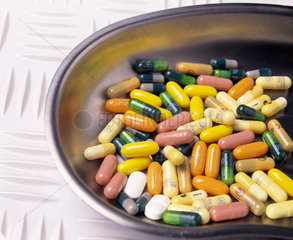 Verschiedenfarbige Tabletten liegen in einer Nierenschale aus Edelstahl