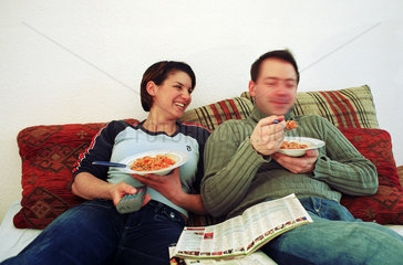 Mann und Frau sehen TV und essen