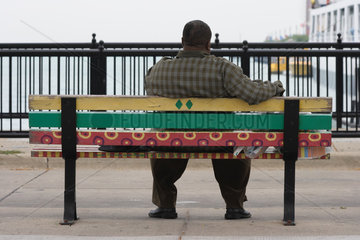 Chicago  USA  ein uebergewichtiger Mann sitzt auf einer bunt angemalten Bank