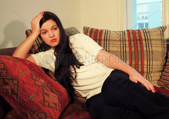 Eine junge Frau in Gedanken auf einer Couch