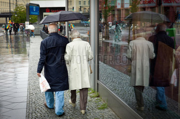 Berlin  Deutschland  Rentnerpaar geht am Alex im Regen spazieren
