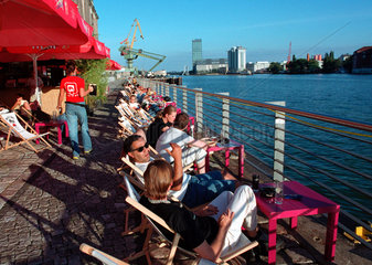 Berlin  Menschen sonnen sich am Osthafen