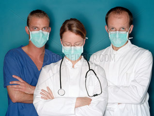 Gruppe von zwei Aerzten und OP Pfleger mit Mundschutz