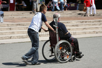 Berlin  Deutschland  Junge schiebt einen alten Mann im Rollstuhl