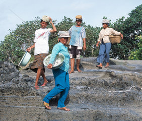 Arbeiterinnen mit Behaeltnissen zum Sandtransport auf dem Kopf  laufen Stufen hinab um Sand vom Strand zu holen
