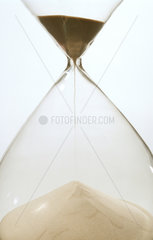 Sand rieselt in einer Sanduhr aus Glas