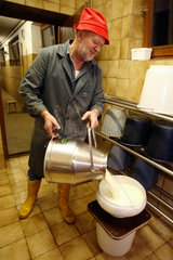 Tirol  ein Bauer giesst frisch gemolkene Milch durch ein Sieb in einen Eimer