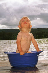 Kleinkind in einer Wanne an einem See in Schweden