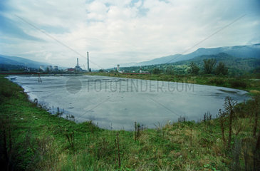 Ein See mit Schlacke  dahinter ein Kohlekraftwerk