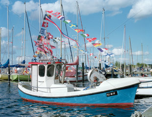 Kleines Fischerboot mit bunten Laenderflaggen