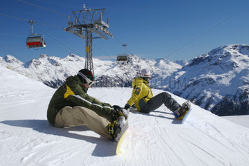 Zwei Snowboarder sitzen auf der Piste