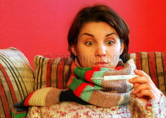 Eine kranke Frau liest vom Fieberthermometer ab