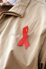 Rote AIDS-Schleife an einer Jacke als Solidaritaetssymbol