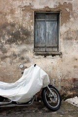 Posada  Italien  abgedecktes Motorrad vor einem verfallenen Haus