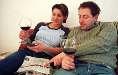 Mann und Frau sehen TV und trinken Wein