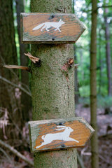 Hinweisschild mit Fuchs und Hasensymbol an einem Baum