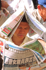 Zuschauer beim Zeitunglesen auf der Rennbahn  Hongkong