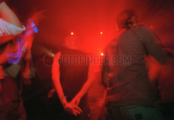 Besucher eines Clubs beim Tanzen in farbigem Licht