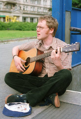 Ein junger Strassenmusiker spielt auf seiner Gitarre