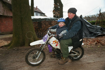 Mutter mit ihrer Tochter faehrt Motorrad im Garten  Norddeutschland