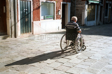 Ein alter Mann ruht in seinem Rollstuhl und geniesst die Sonne